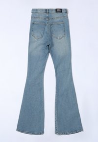 Flared denim jeans in light blue, featuring a five-pocket design, contrasting stitching, and a black label at the waistband.