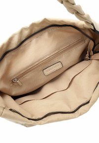 Beige kankainen laukku, jossa on punottu hihna, sisältää sisäisen vetoketjutaskun ja sileän vuoren. Vetoketjukiinnitys yläreunassa.