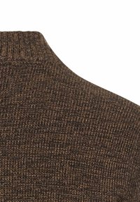 Brauner Strickpullover mit hohem Kragen, strukturiertem Gewebe und einem subtilen Muster, das eine Mischung aus dunklen und hellen braunen Fasern zeigt.
