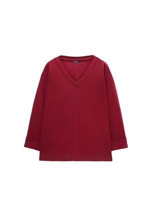 Czerwony sweter z długim rękawem i dekoltem w serek, z centralnym szwem i mankietami na rękawach, ułożony płasko na białym tle.