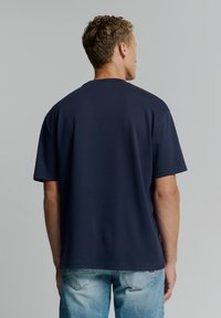 Marineblauwe katoenen t-shirt met korte mouwen en een ronde halslijn, met een relaxed fit en een gladde textuur. Achteraanzicht weergegeven.