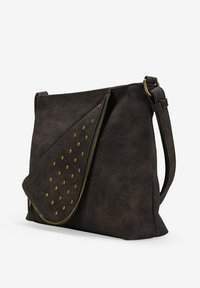 Bolso de hombro de cuero marrón oscuro con una superficie texturizada, tapa diagonal, tachuelas doradas y una cremallera dorada a lo largo del borde.