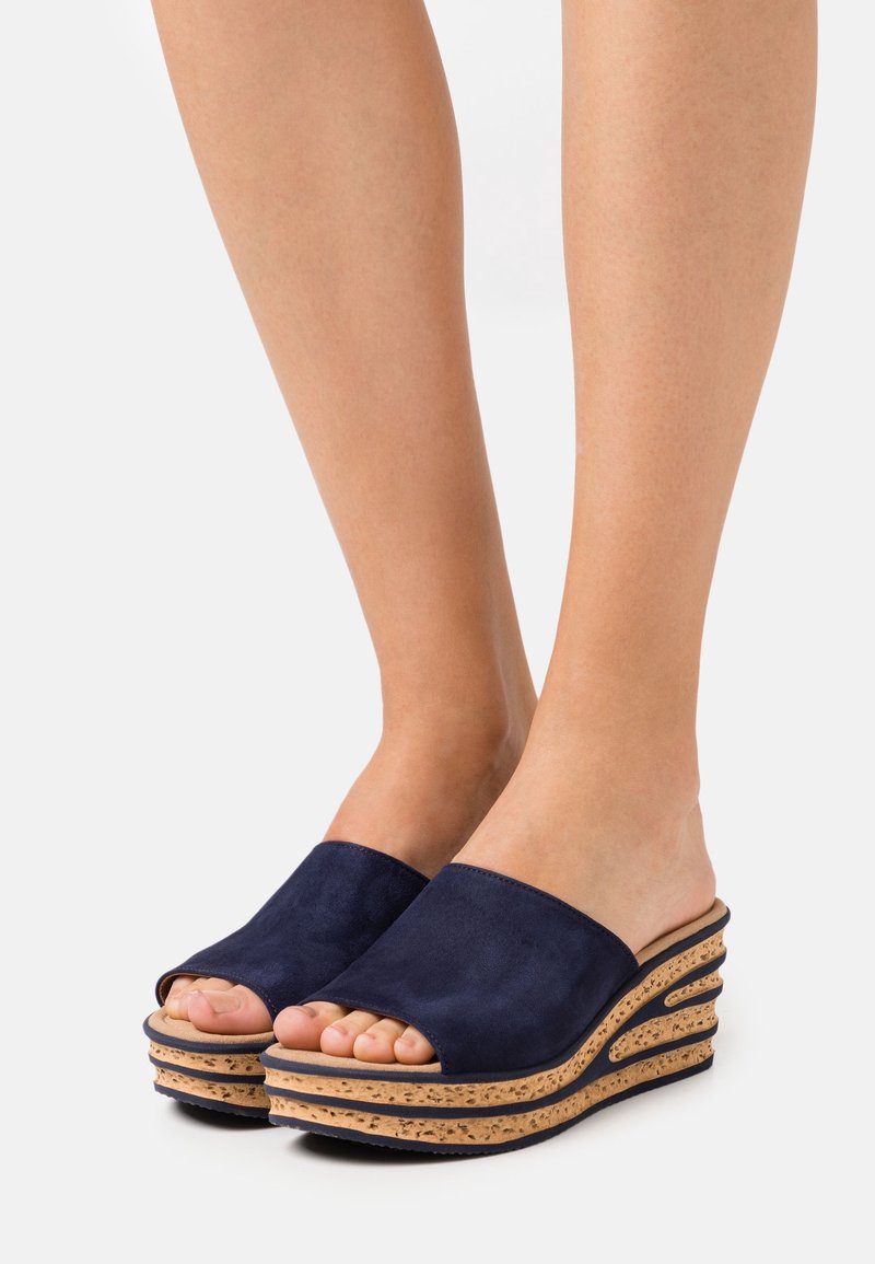 Sandales compensées en daim bleu marine avec bout ouvert, comprenant une semelle intermédiaire en liège et un design superposé incurvé pour plus de texture et d'intérêt visuel.