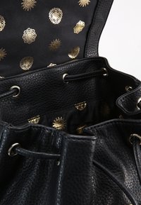 Schwarze Leder-Eimer-Tasche mit strukturierter Außenfläche, goldakzentierter Stoffauskleidung mit dekorativen Mustern. Verstellbarer Kordelzugverschluss.
