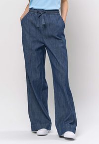 Pantaloni din denim cu croială largă, de culoare albastru închis, prevăzuți cu talie elastică cu șnur, buzunare laterale și textură netedă a materialului.