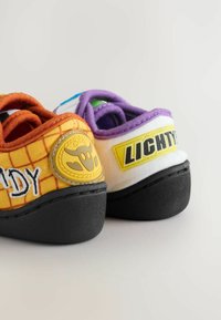 Colorful shoes featuring a yellow grid pattern with "CANDY" text and a logo, and a white side with "LICHTY." Accented with purple and black details.