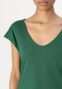T-shirt verde in cotone con scollo a V e maniche corte, caratterizzato da una superficie liscia e una vestibilità comoda.