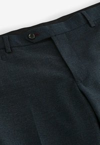 Pantalons ajustés bleu marine avec une texture lisse, une fermeture à un bouton et des passants de ceinture à la taille.