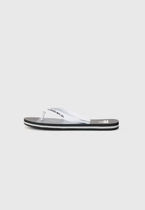 Black flip-flop featuring white straps with a logo, textured footbed, and a contrasting white and black sole with a thin striped detail.