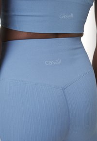 Ljusblå randig sporttop och högmidjade leggings med diskret branding. Tyget verkar elastiskt med en slät textur och en skräddarsydd passform.