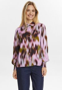 Långärmad blus i ljusrosa med abstrakta mönster i mörkbrunt och grönt. Har en krage och knappar framtill. Texturerade manschetter.