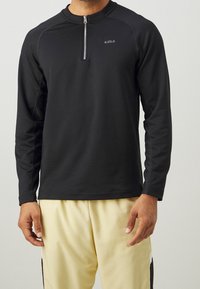 Schwarzes langärmeliges Sportshirt mit einem Viertel-Reißverschluss am Kragen und einem Logo auf der Brust. Hergestellt aus weichem, atmungsaktivem Stoff mit glatter Textur.