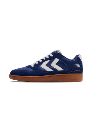 Baskets en cuir et daim bleu avec des accents en chevron blanc, des lacets blancs et une semelle en caoutchouc marron avec un logo en relief au niveau du talon.