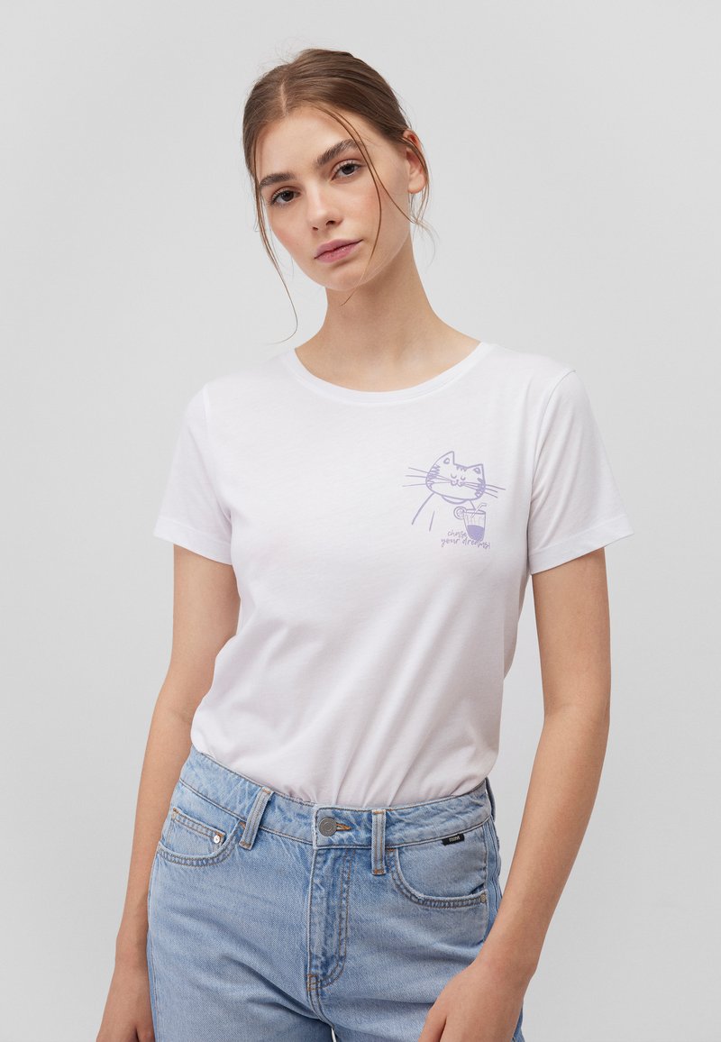 White cotton t-shirt with short sleeves, featuring a light purple cat graphic on the chest. Paired with light blue denim jeans.