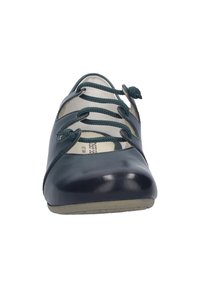 Zapato plano de cuero azul marino con puntera redondeada y cordones decorativos verde oscuro cruzados sobre la parte delantera superior.