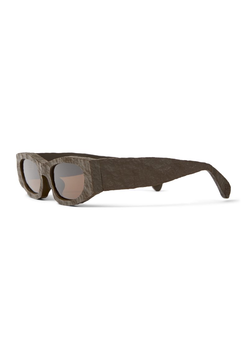 Bronze zonnebril met een textuur en een onregelmatig frame, oversized ronde lenzen en dikke pootjes. Gemaakt van een milieuvriendelijk materiaal.
