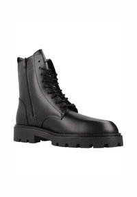 Botas de cuero negro con cordones y tobillo alto, cremallera lateral, suela gruesa negra y textura suave. Presentan costuras reforzadas y un diseño minimalista.