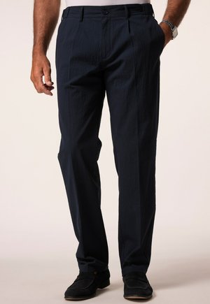 Pantaloni blu navy in tessuto testurizzato con vestibilità dritta; presentano una chiusura a bottone e tasche laterali. Scarpe nere completano l'outfit.