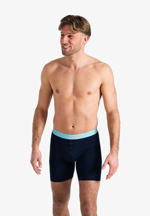 Marineblaue Herrenboxershorts mit einem hellblauen Bund, auf dem der Text "HAPPY SHORTS" in Orange aufgedruckt ist. Glattes Material, mit einer Länge bis zur Mitte des Oberschenkels.