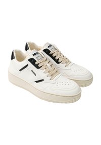 White leather sneakers with black accents, round toe, perforated uppers, and beige laces. Features a thick textured sole and branding on the side.