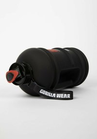 Black water bottle with a textured grip, red flip-top lid, and a black strap labeled "GORILLA WEAR." Wide cylindrical shape, durable material.