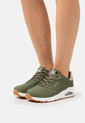 Baskets de sport vertes avec une finition texturée, un design léger et des accents en or rose. Elles disposent d'une semelle rembourrée et d'un dessus respirant.