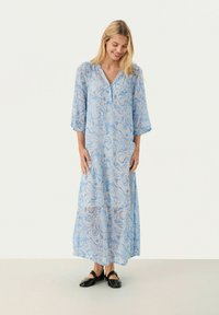 Pikk, helesinine kleit paisley-mustriga, V-kaelusega ja kolmeveerandsleevedega. Kantud mustade kingadega, tehtud voolavast kangast.