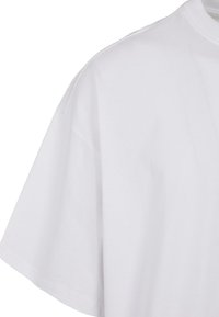 Hvid bomulds T-shirt med korte ærmer, rund halsudskæring og en afslappet pasform. Glat tekstur, ingen synlige mønstre eller logoer.