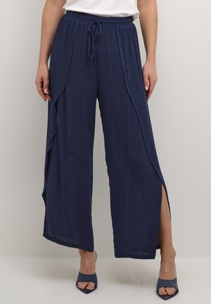 Marineblauwe wijde broek met een trekkoord in de taille en zijsplitten. Gemaakt van een lichtgewicht stof, met een gladde textuur en een vloeiend ontwerp.