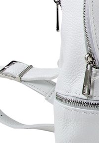 Weißer Kunstleder-Rucksack mit strukturiertem Finish, silbernen Reißverschlussbeschlägen und einem flachen, verstellbaren Schultergurt mit Schnalle.