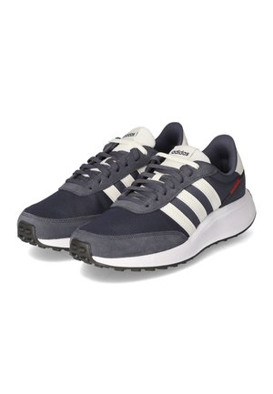 Paire de baskets Adidas gris foncé et blanc avec des bandes blanches, des lacets et des semelles rembourrées, présentées légèrement en angle.