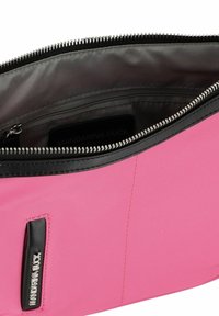 Bolsa de tela rosa con cierre de cremallera, acentos negros y forro texturizado. Presenta una etiqueta interior con la inscripción 'Mandarina Duck'.