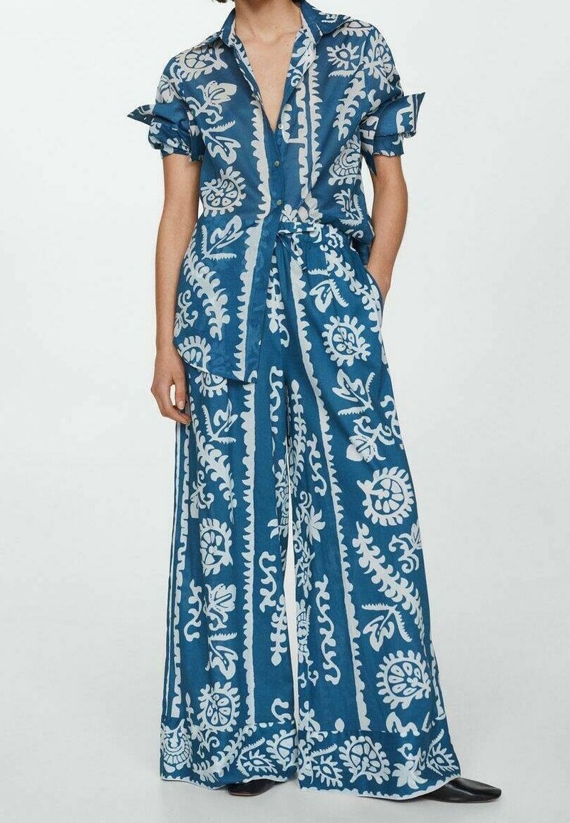 Ensemble deux pièces à imprimé bleu, composé d'un tissu léger ; comprend une chemise à manches courtes avec col et un pantalon à jambes larges ornés de motifs floraux blancs.