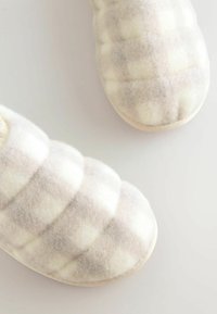 White and beige checkered fabric slippers with a soft, fuzzy texture, rounded toe, and minimalistic sole.