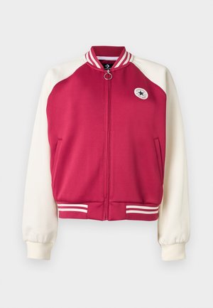 Veste universitaire bordeaux et blanche à fermeture éclair, avec col et poignets rayés, deux poches latérales, et un petit patch logo Converse All Star sur la poitrine.