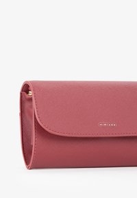 Portafoglio rosa testurizzato con pattina magnetica, caratterizzato da un logo dorato e un design elegante. Finitura liscia con uno stile minimalista e senza hardware visibile.