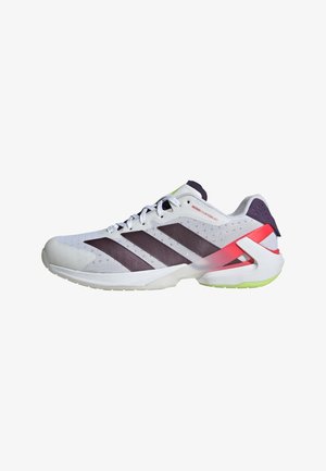 Scarpa da ginnastica bianca con strisce nere, supporto al tallone rosso, accenti verde chiaro sulla suola e tomaia in rete, vista dal lato esterno.
