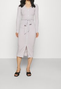 Hellgraues, langärmliges Kleid mit V-Ausschnitt, Knöpfen vorne und einem taillierten Bindegürtel. Es hat eine mittellange Länge und einen Schlitz am vorderen Saum.