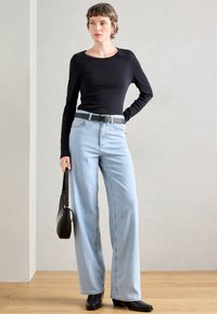 Μαύρη μπλούζα με μακριά μανίκια, ανοιχτό μπλε παντελόνι με φαρδιά γραμμή, μαύρη ζώνη, μαύρη τσάντα και μαύρα παπούτσια με τακούνι. Απλό σχέδιο, λεία υφή και κακό σχέδιο.