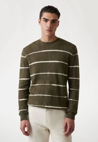 Olivgrüner Strickpullover mit weißen Streifen, Rundhalsausschnitt, langen Ärmeln und gerippten Bündchen. Weiche Textur und lockere Passform.