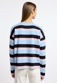 Sweter w paski w kolorach niebieskim, czarnym i różowym. Posiada długie rękawy, luźny krój oraz miękką teksturę, zaprezentowany od tyłu.