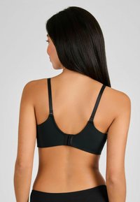 Sostén negro con tirantes ajustables, tela suave y un cierre de gancho y ojo en la parte posterior. Presenta un diseño sin costuras.