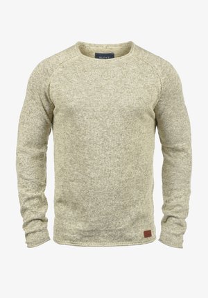 Šviesiai smėlinis megztinis su ilgomis rankovėmis, apvaliu iškirpimu ir tekstūruotu paviršiumi. Pridedama maža ruda odinė detalė ant apačios.