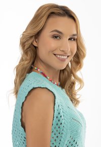 Maglia azzurro chiaro lavorata a maglia con un design a motivo, dotata di scollatura rotonda e maniche corte. Una collana di perline colorate aggiunge dettagli.