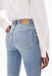 Light blue high-waisted jeans with a fitted silhouette. Features a leather label on the waistband and rear pockets with stitch detailing.