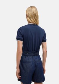 Top de manga corta azul marino con borde festoneado y pantalones cortos de denim de cintura alta. Presenta una textura suave y bolsillos traseros.