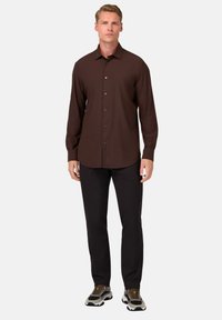 Rudas ilgomis rankovėmis marškiniai su apykakle, derinami su juodomis kelnėmis ir daugiaspalviais sportbačiais. Lygus audinys, prigludusi forma.