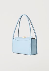 Τσαντάκι χειρός από ανοιχτό μπλε δέρμα με δύο μακριές λαβές και στρογγυλό χρυσό κούμπωμα, παρουσιασμένο σε απλό λευκό φόντο.