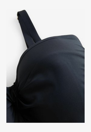 Czarny biustonosz wypełniony podkładkami z gładkiego materiału, z regulowanymi ramiączkami i okrągłym kształtem miseczek, z delikatnymi szwami i bez widocznych elementów metalowych.