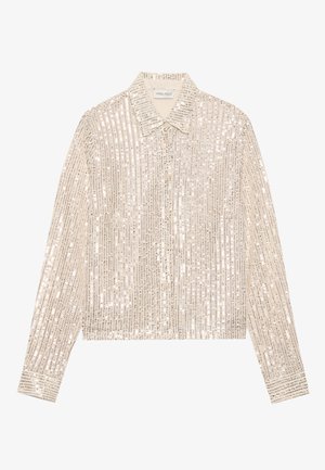 Beige flitteres ing, klasszikus gallérral, hosszú ujjakkal és gombos záródással, függőleges csíkos mintázattal az anyagon.